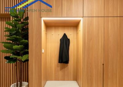 Modern entryway with wooden paneling, coat hooks, and a potted plant