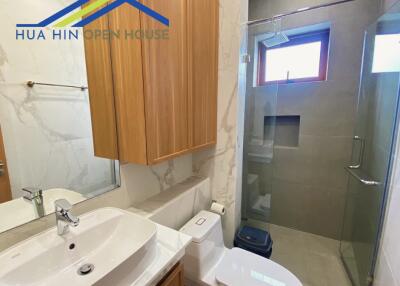 Modern bathroom with glass shower, wooden cabinet, and backlit mirror