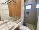 Modern bathroom with glass shower, wooden cabinet, and backlit mirror