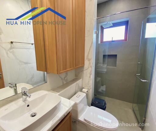 Modern bathroom with glass shower, wooden cabinet, and backlit mirror