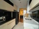 Modern kitchen with black and white cabinetry and view into dining area