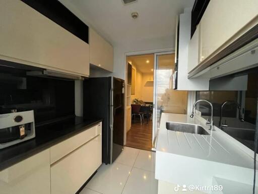 Modern kitchen with black and white cabinetry and view into dining area