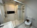 Modern bathroom with glass shower, sink, and toilet