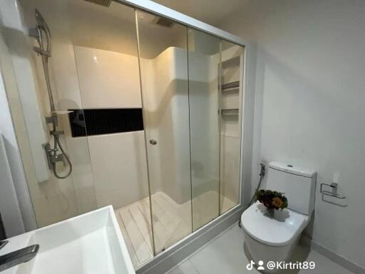 Modern bathroom with glass shower, sink, and toilet