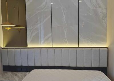 Modern bedroom with upholstered headboard and marble accent wall