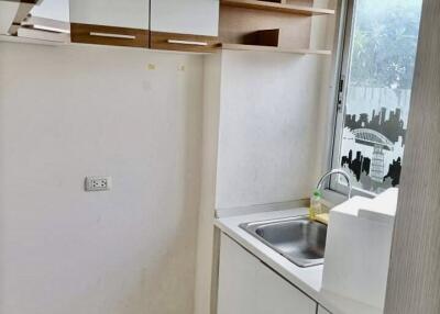 Small modern kitchen with white cabinets and a window