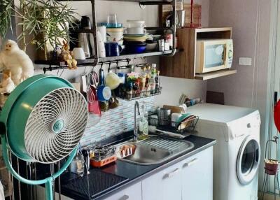 Small kitchen with various appliances and a fan