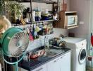 Small kitchen with various appliances and a fan