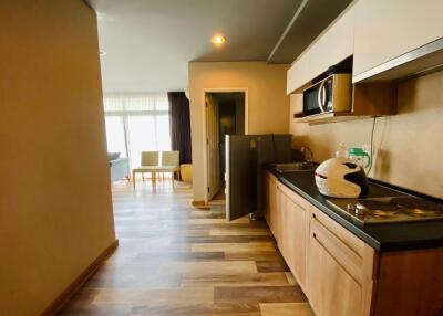 Modern kitchen space with wooden cabinets and open layout leading to a living area