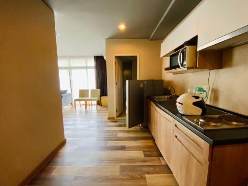 Modern kitchen space with wooden cabinets and open layout leading to a living area