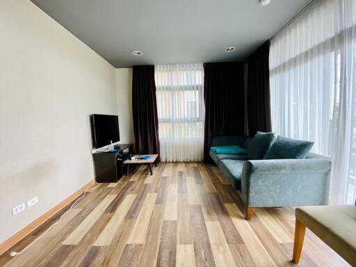 Modern living room with TV, couch, and large windows