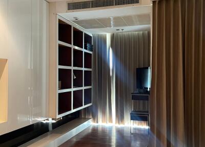 A spacious living room with a television, a large curtain, and shelves.