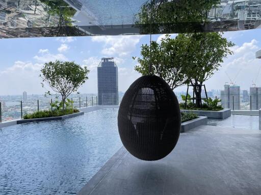 Rooftop pool area with a hanging chair and city view