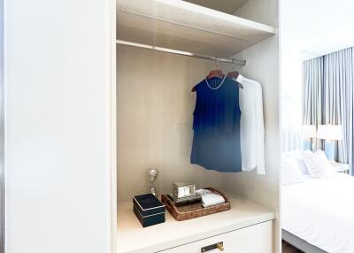 Open wardrobe in a bedroom with hanging clothes and shelves