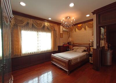 Elegant master bedroom with wooden flooring, ornate furniture, and a chandelier