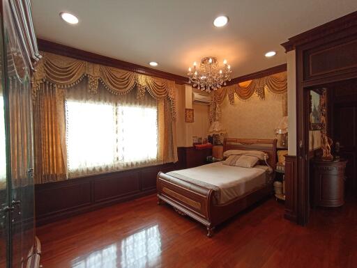 Elegant master bedroom with wooden flooring, ornate furniture, and a chandelier