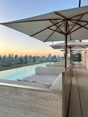 A rooftop pool area with umbrellas and an expansive city view