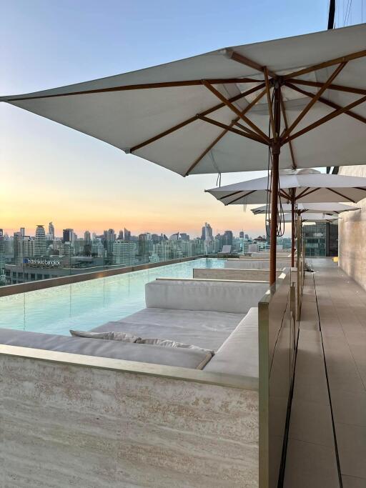 A rooftop pool area with umbrellas and an expansive city view