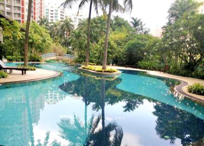 Outdoor pool in a landscaped area with trees and apartment buildings in the background