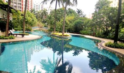 Outdoor pool in a landscaped area with trees and apartment buildings in the background