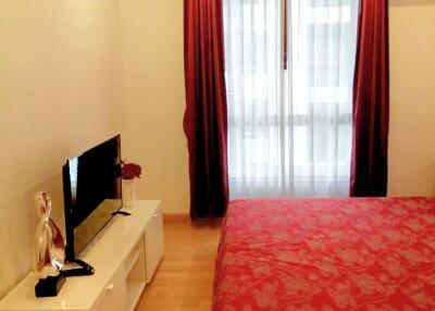 Bedroom with a bed, TV, and red curtains