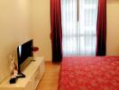 Bedroom with a bed, TV, and red curtains