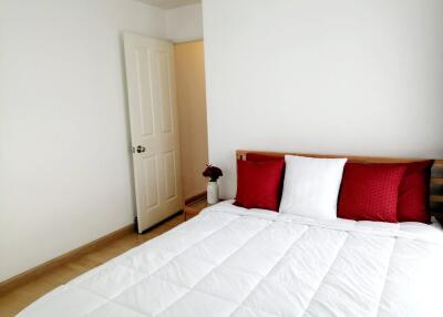 Bedroom with white bedspread and red pillows