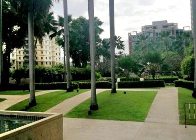 Well-maintained green space with palm trees and apartment buildings