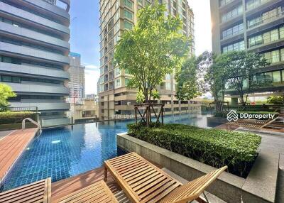 Outdoor pool area with lounge chairs and surrounding buildings