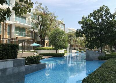 Outdoor pool area with modern apartments and greenery