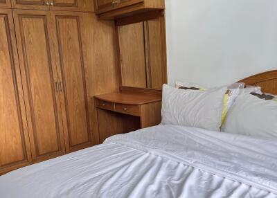 Spacious bedroom with wooden built-in wardrobe and white bedsheets