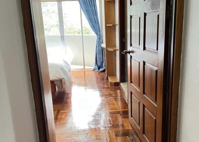 Bedroom with wooden flooring and door, blue curtains, and a window view