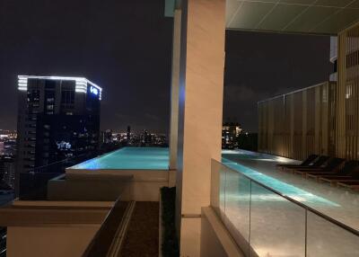 Night view of rooftop infinity pool with city skyline