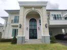 Front view of a two-story house with a manicured lawn and arched entrance