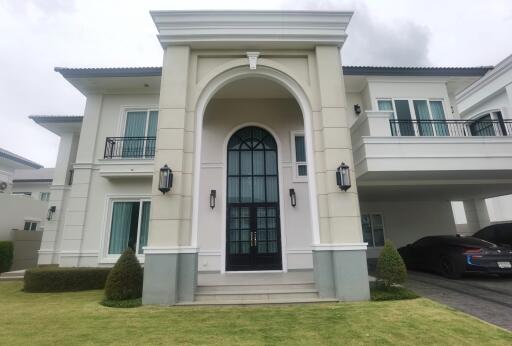 Front view of a two-story house with a manicured lawn and arched entrance