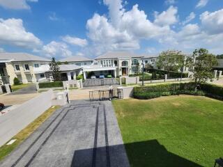 A residential neighborhood with multiple houses, driveway, and green lawns under a blue sky with clouds