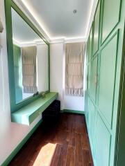 Bedroom with large mirror and built-in green wardrobes