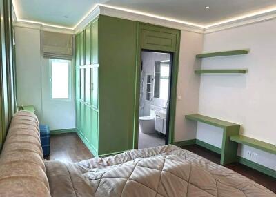 Bedroom with green cabinetry and view into en-suite bathroom