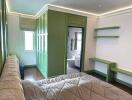 Bedroom with green cabinetry and view into en-suite bathroom