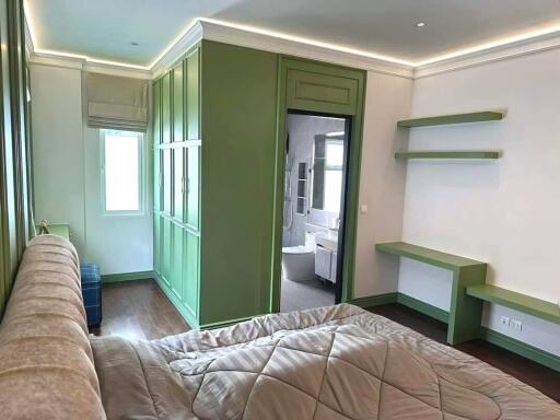 Bedroom with green cabinetry and view into en-suite bathroom