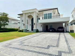 Exterior view of a luxurious house with a spacious driveway, landscaped garden, and garage