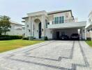 Exterior view of a luxurious house with a spacious driveway, landscaped garden, and garage