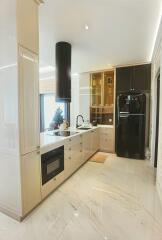 Modern kitchen with marble flooring, black refrigerator, and decorative items