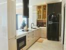 Modern kitchen with marble flooring, black refrigerator, and decorative items