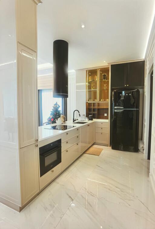 Modern kitchen with marble flooring, black refrigerator, and decorative items