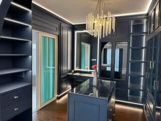 Walk-in closet with navy blue cabinets and chandelier