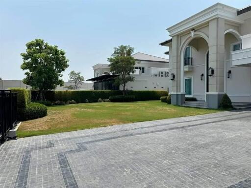 Exterior view of a luxury home with a spacious driveway and well-manicured lawn