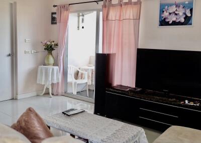 Living room with a television, coffee table, and sliding door leading to a small outdoor area