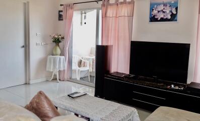 Living room with a television, coffee table, and sliding door leading to a small outdoor area