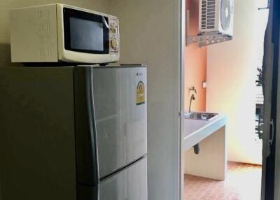 Small kitchen with microwave, refrigerator, and air conditioning unit